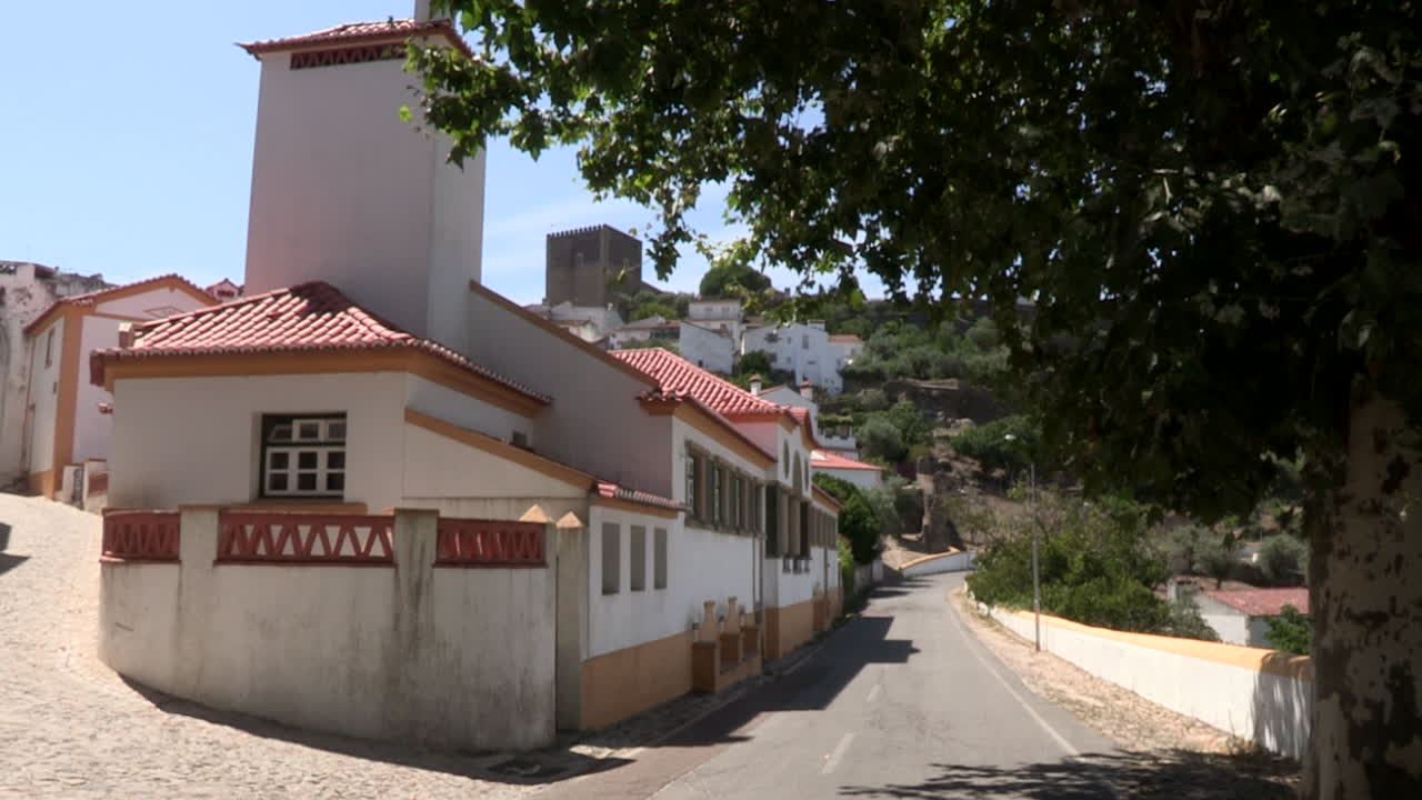 pequenas casas antigas renovadas e pintadas de branco e amarelo na encosta, com castelo de vide ao fundo