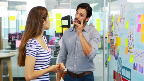 male and female executive discussing over whiteboard