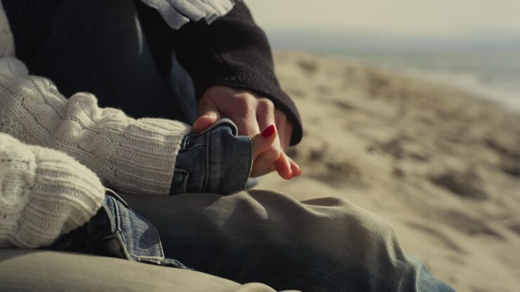 Lovers holding hands together on sand beach. Couple relaxing on sea coast shore.