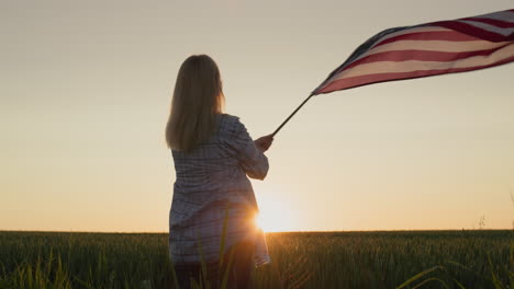 happy woman waving american flag on wheat field background. july 4th - independence day usa concept