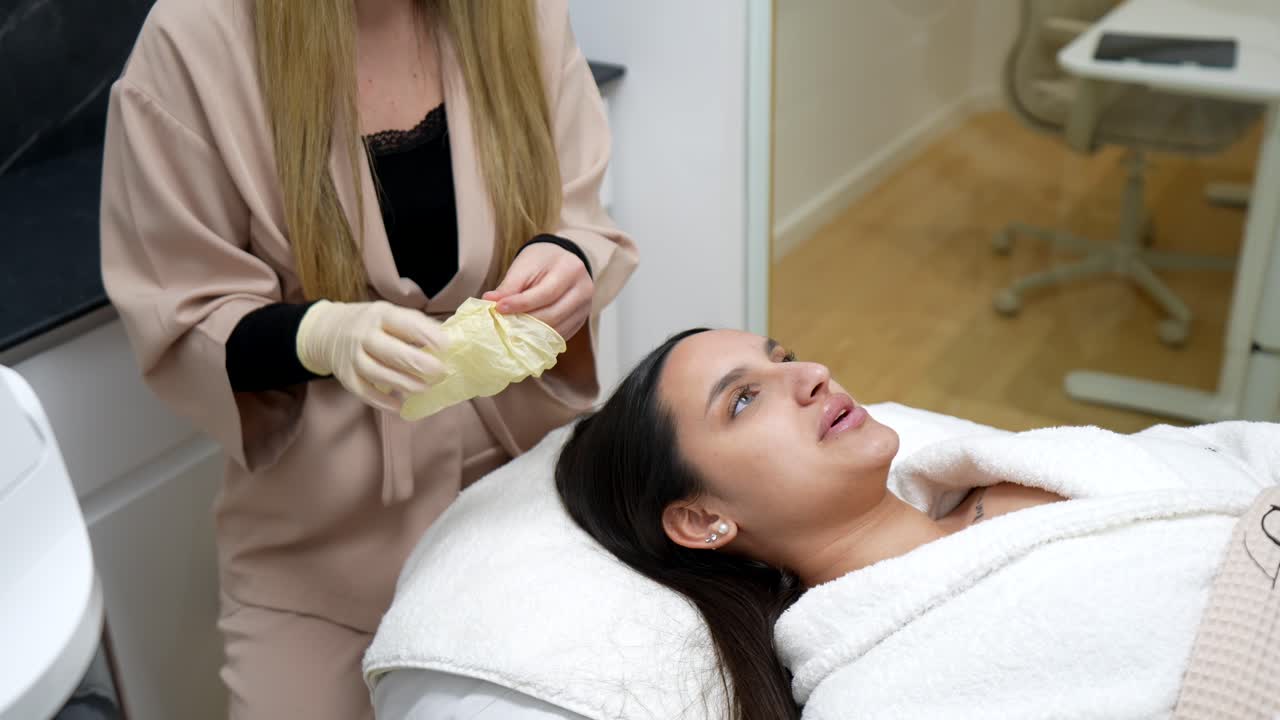 Esteticista poniéndose guantes antes de un tratamiento de spa