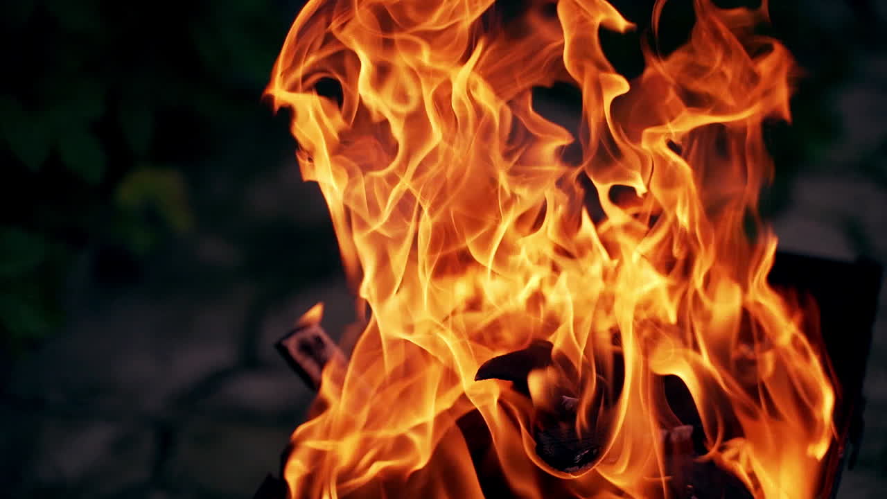 Red and yellow flame burning at night. Vivid campfire in darkness. Beautiful fire burns brightly. Orange flames surging up.