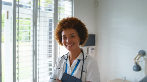 Portrait-Of-Smiling-Female-Nurse-Wearing-Uniform-With-Digital-Tablet-In-Private-Hospital-Room