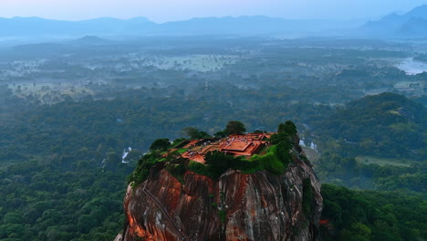 sigiriya fortress ruins with numerous tourists walking by. picturesque mount standing out from the hazy landscape of sri lanka. aerial view.