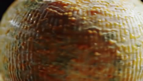 a close-up exploration of a textured, delicious cheese wheel showcasing its intricate surface details and vibrant colors, inviting a sensory experience of flavor and aroma