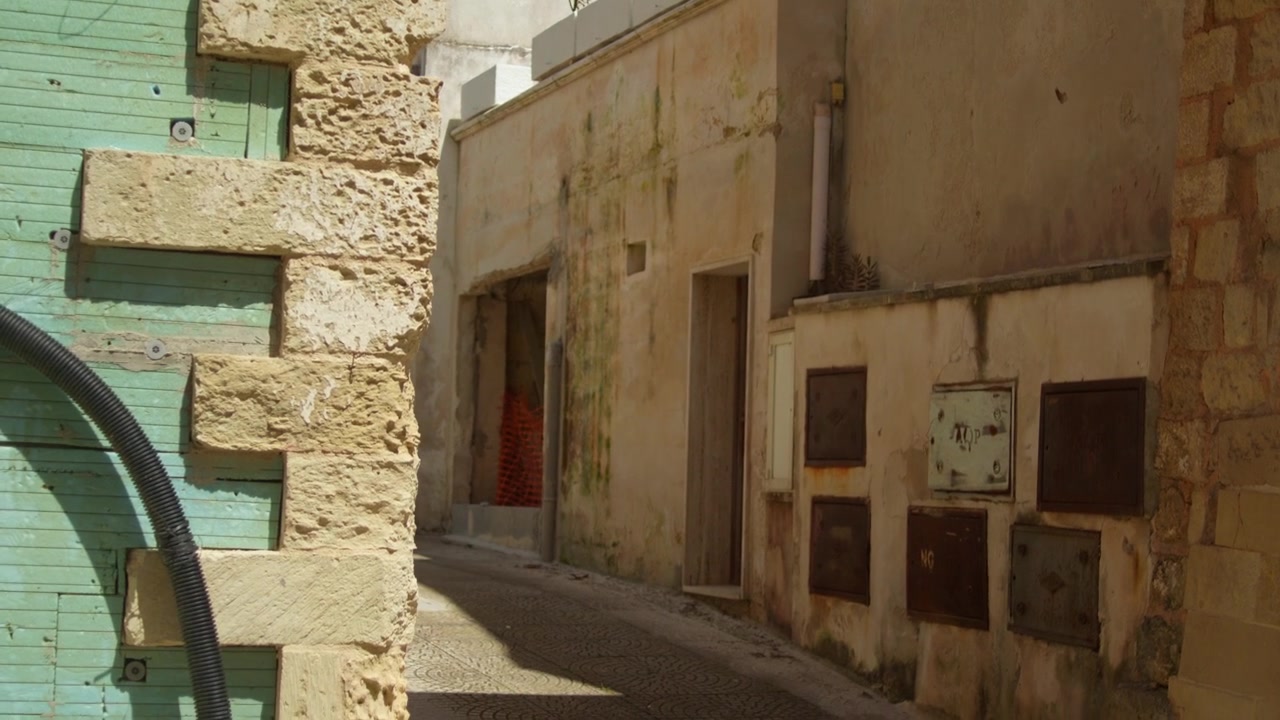 Storico vicolo in pietra calcarea che mostra edifici in pietra consumati dal tempo, architettura tradizionale e strade strette a Brindisi, Puglia, Italia, ripresa panoramica lenta verso il basso con gimbal