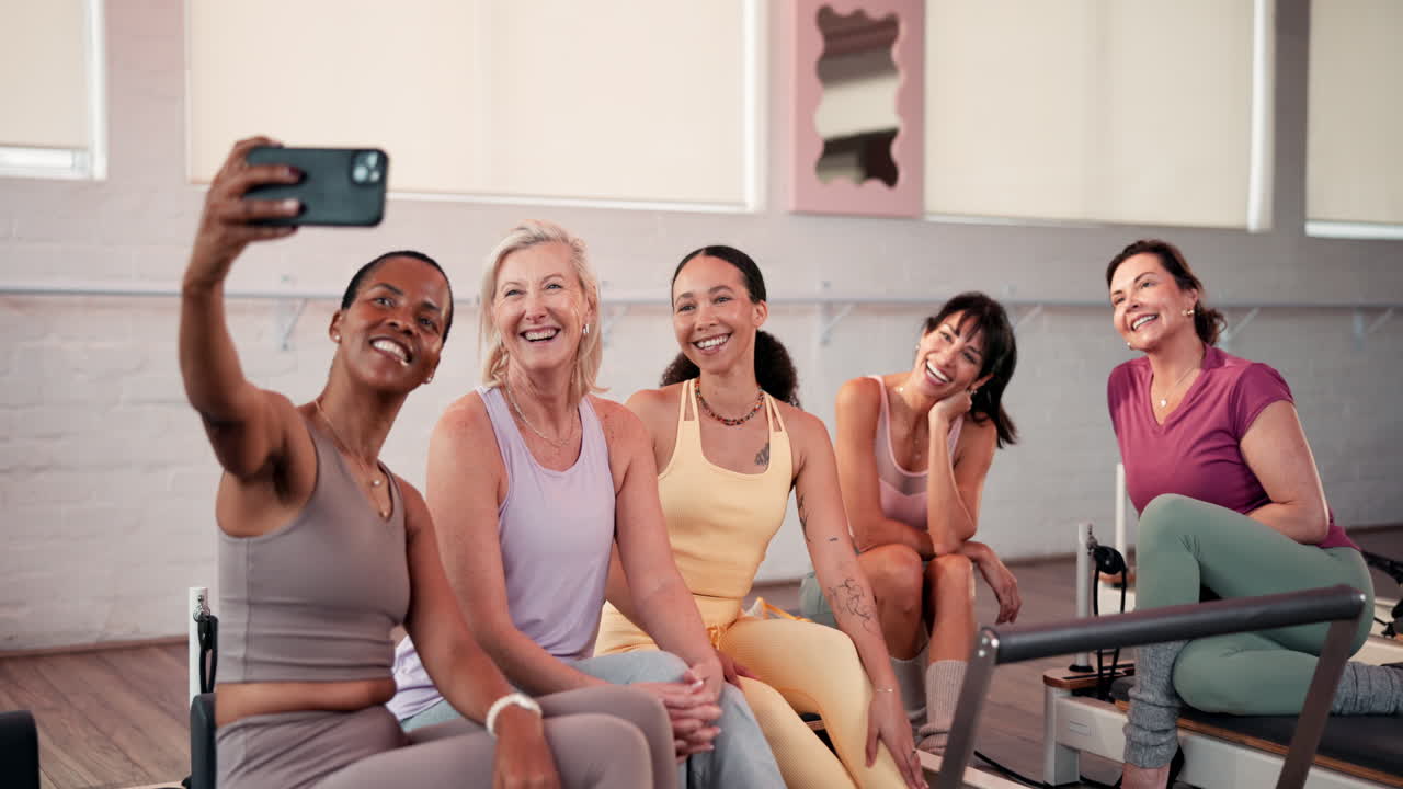 Gruppo di donne che si godono una sessione di Pilates e guardano un telefono