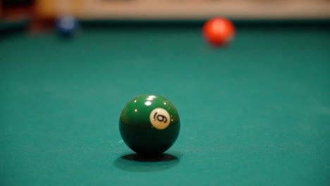 slow motion billiards cue ball passes green 6 ball and hits purple 4 ball with spin and full contact close up on pool table with green felt from a low angle