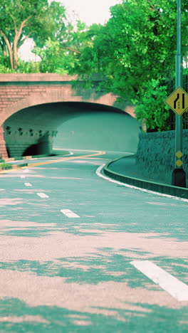 a road curves under a bridge, with trees on either side.