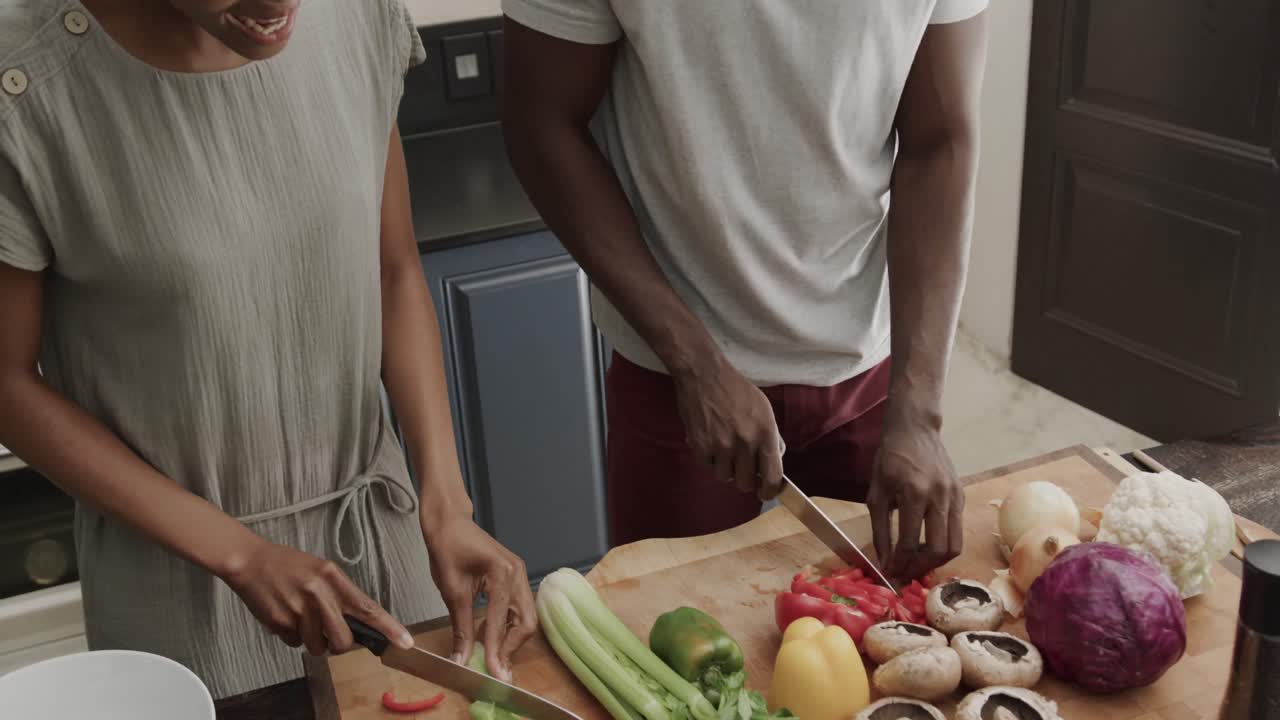 Happy african american couple cutting vegetables together in ktichen in slow motion