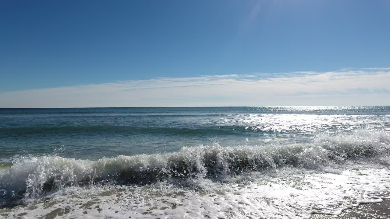 맑고 화창한 날 잔잔한 파도를 향해 날아가는 드론 샷