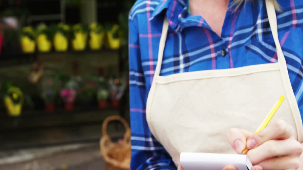 florista que toma pedidos por teléfono móvil