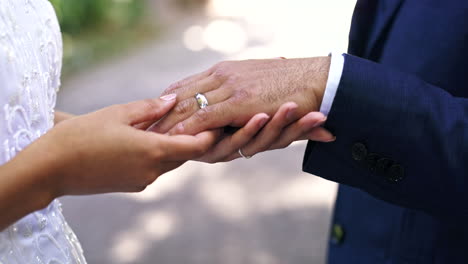 marriage, wedding ring and hands of couple in park