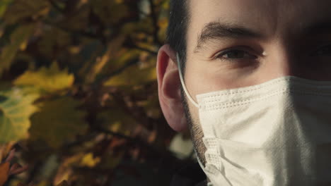 Caucasian-man-with-face-mask-looking-into-camera,-outside-extreme-closeup-view,-copy-space