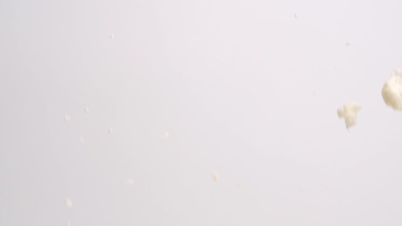 pedazos rotos de flores de coliflor lloviendo sobre fondo blanco en cámara lenta
