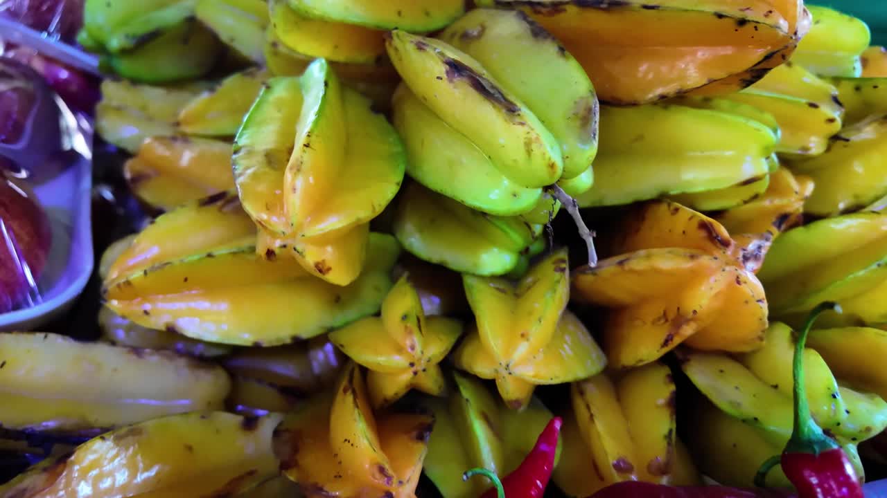 Close-up of starfruits and red chili peppers, exotic tropical fruits at food market.
