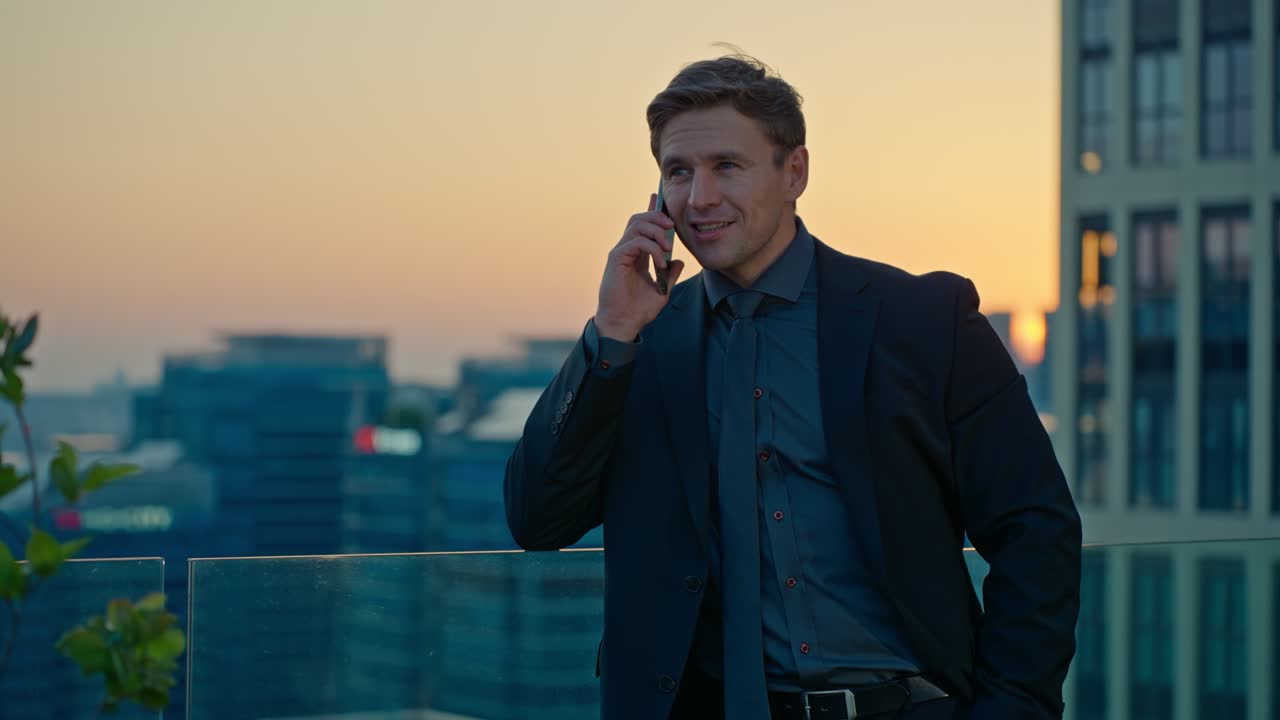 Receiving good news on a phone call, an inspiring Caucasian professional man laughs and makes a power fist gesture of success in a slow-motion shot on a Seoul rooftop