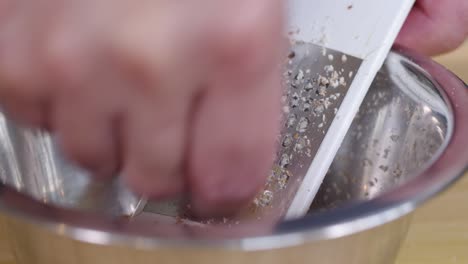 Grating-almonds-into-metal-bowl-to-make-almond-powder