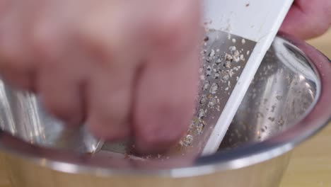 grating almonds into metal bowl to make almond powder