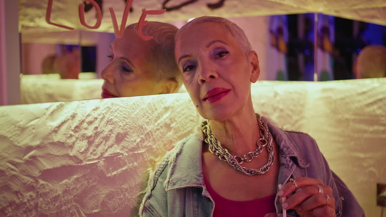 Smiling senior enjoying bar evening. Portrait stylish mature woman stir cocktail