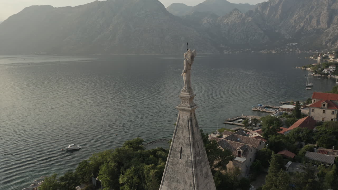 A beautiful view of the Bay of Kotor with a church spire in the foreground and Dinaric Alps in the background in Kotor, Montenegro