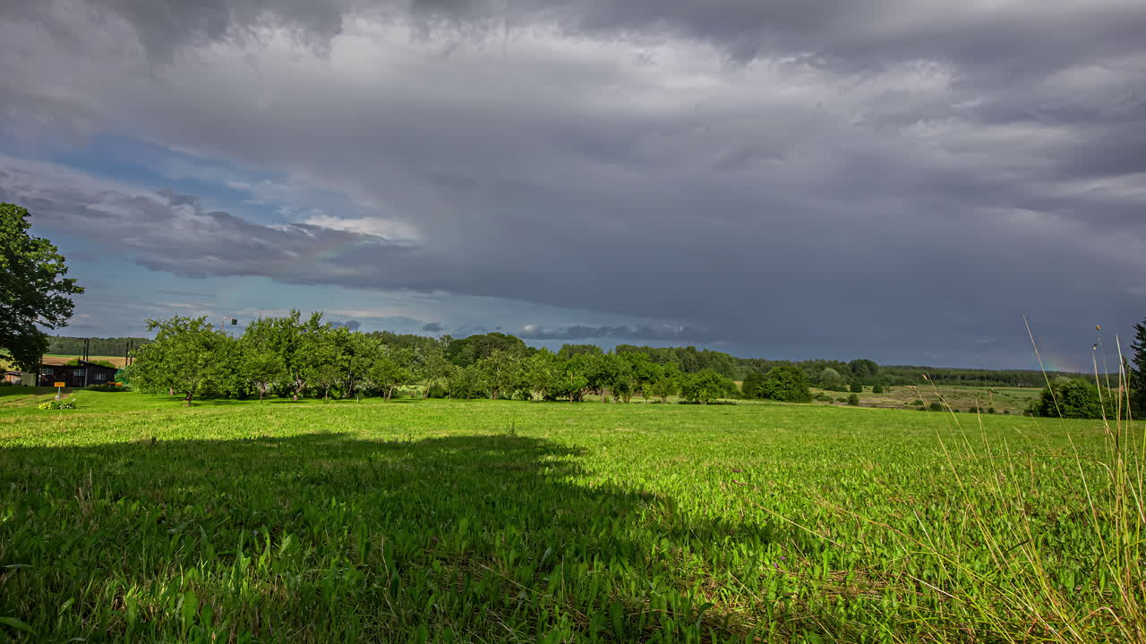 시골 풍경 위로 어두운 구름 운동 위에 푸른 잔디 필드의 정적인 보기