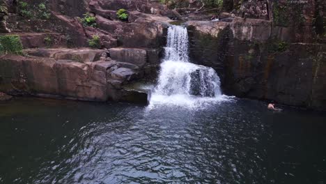 hombre nadando en el lago frente a la cascada