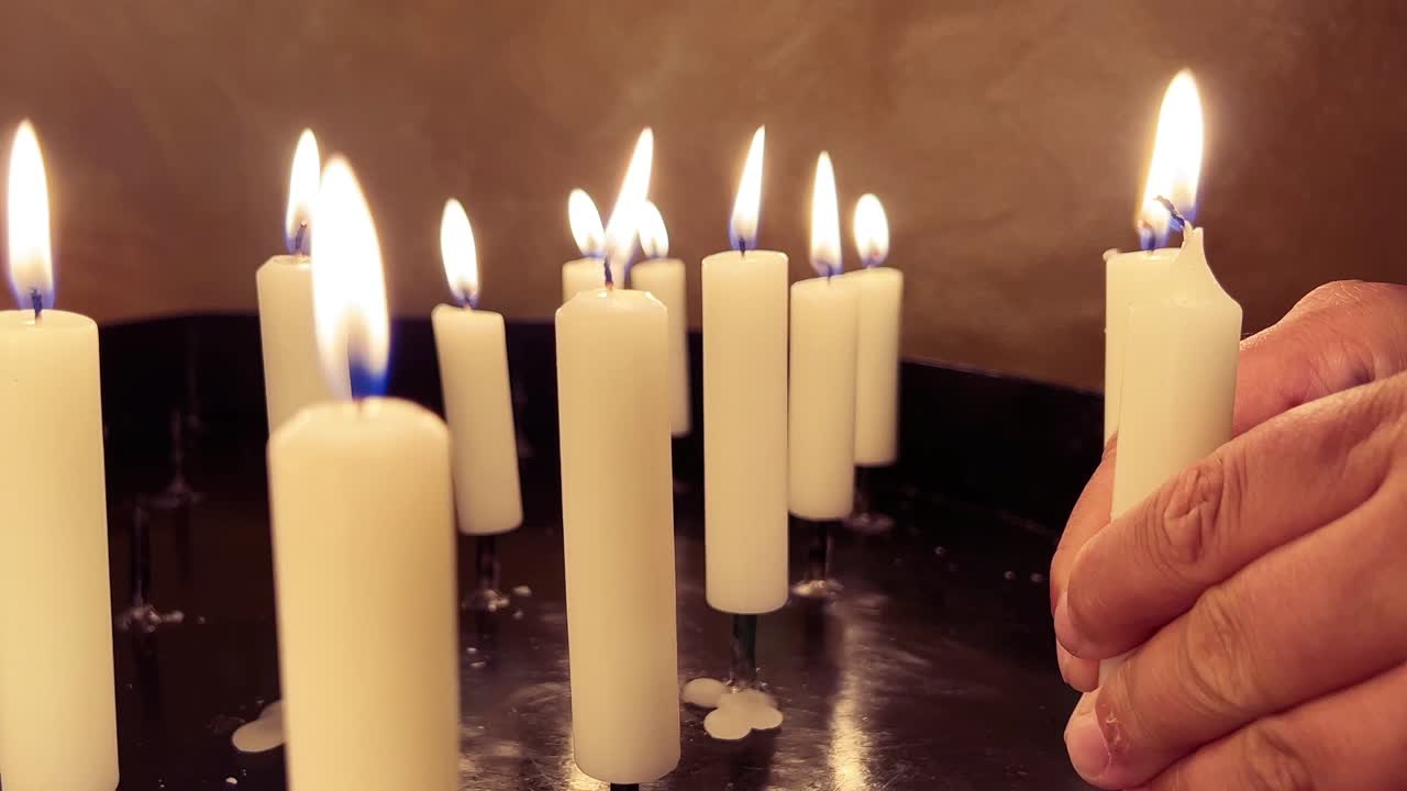 Mani giunte in preghiera con una candela votiva