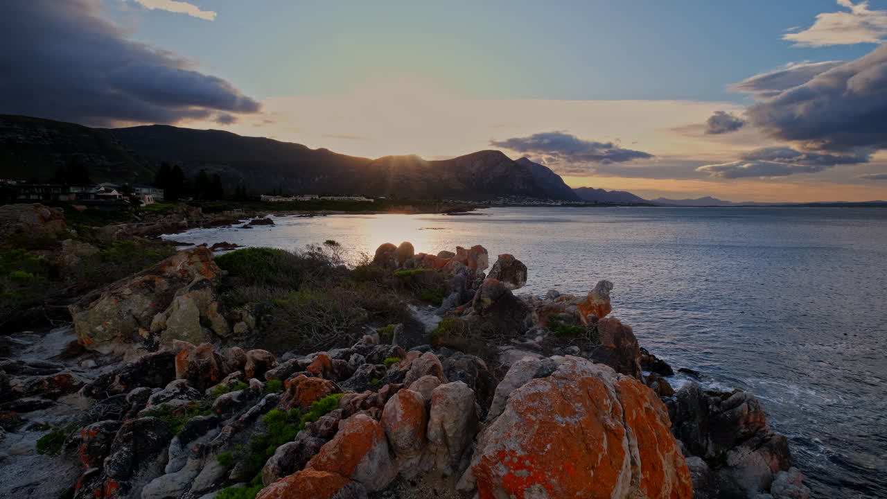 Lichen covered rugged coastal rocks with sunrise view over Walker Bay in Hermanus