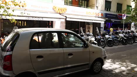 a car drives past parked scooters in naples