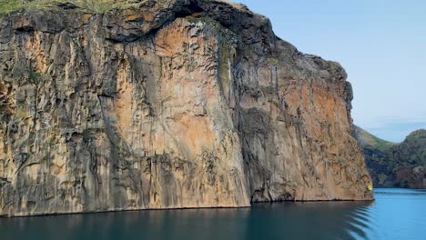 majestic cliff face of vestmannaeyjar under soft light, blue water in foreground