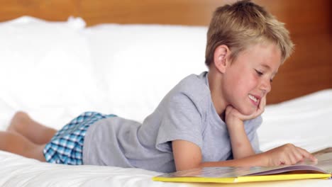 Little-boy-lying-on-bed-reading-a-book