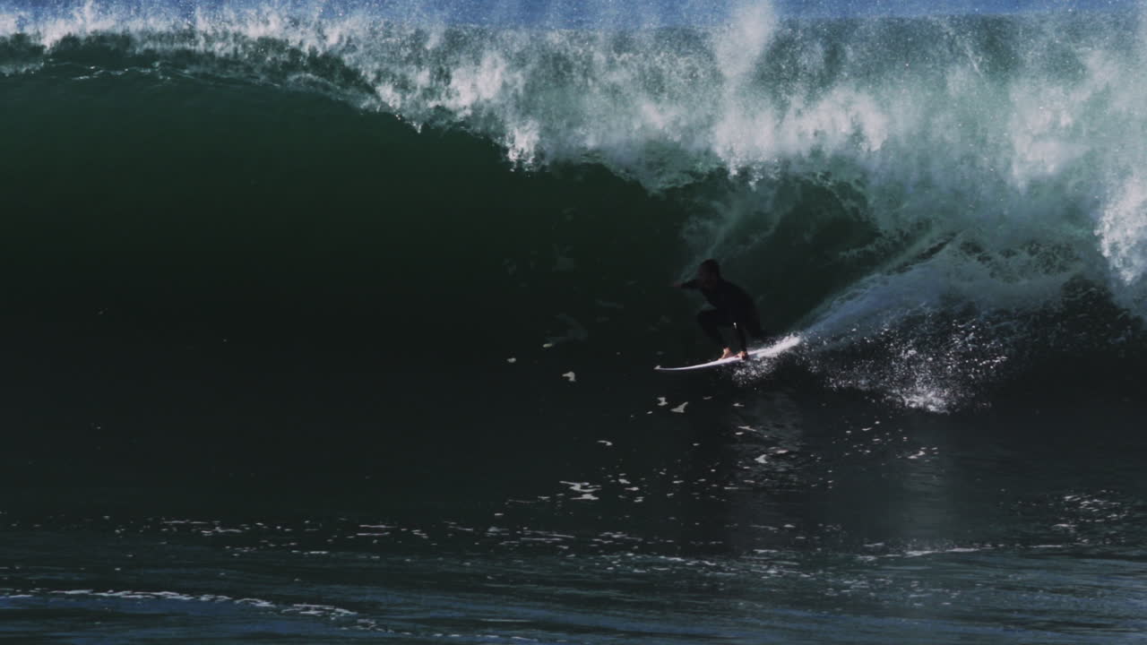 Tight tube forms dramatic funnel over rider who disappears into dark barrel