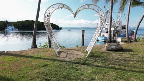 creative drone view flying through a love heart shape structure over the calm waters of a coastal fishing village