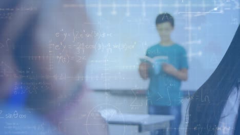 Mathematical-equations-floating-against-caucasian-boy-reading-a-book-in-class-at-elementary-school