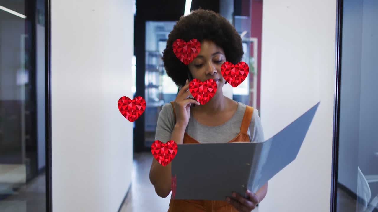 iconas de corazón de cristal rojo sobre mujer afroamericana leyendo un documento y hablando en teléfono inteligente