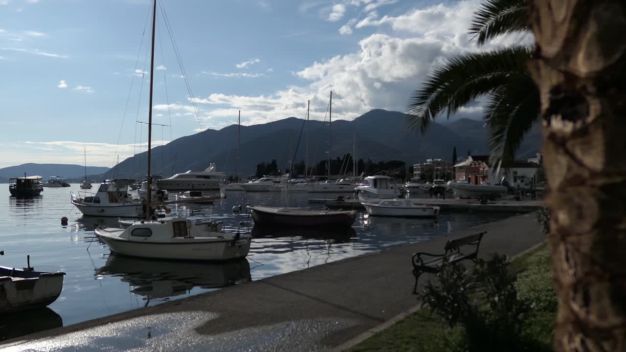 Barche ormeggiate al porto turistico, passeggiata sul lungomare, inquadratura rivelatrice, Tivat, Montenegro.