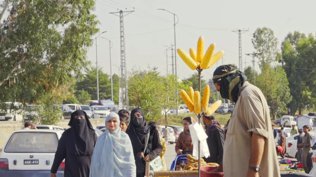 Close-up View of Street Cart Vendor Offering Fresh Grilled Corn on the Cob in a Busy City Square