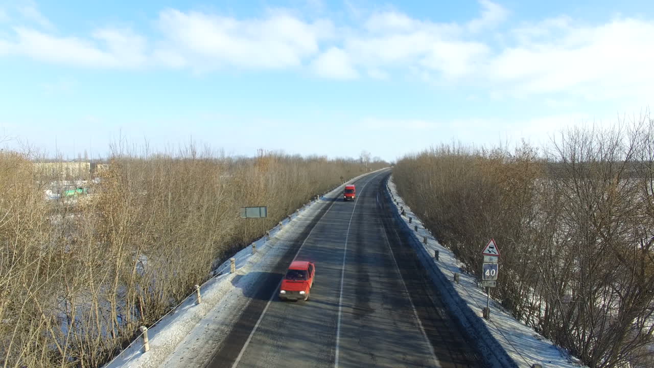 Highway with cars in winter. Winter road through snowy fields and forests