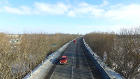 highway with cars in winter. winter road through snowy fields and forests