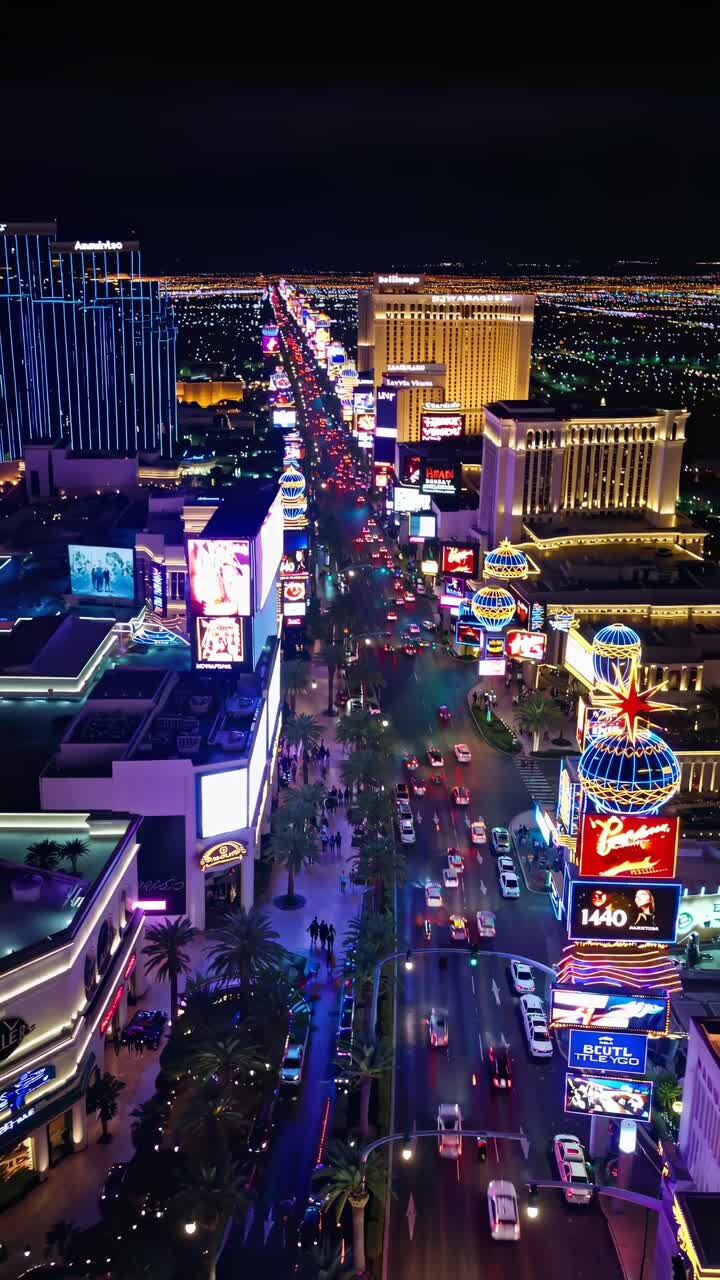 Aerial view of a vibrant city street at night, illuminated by neon lights
