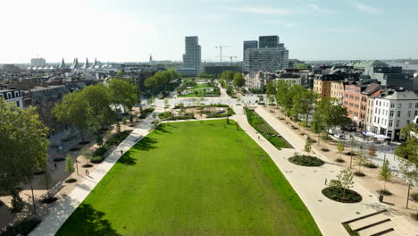 Backwards-drone-dolly-shot-over-a-green-meadow-in-a-park-in-Antwerp-on-a-sunny-day