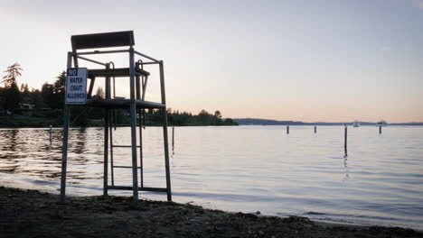 toma manual de un puesto de salvavidas vacío con vista al lago tranquilo al atardecer con un cartel que dice &quot;no se permiten embarcaciones