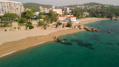 Main-beach-of-Platja-de-Aro-on-the-Costa-Brava-of-Girona-day-with-calm-sea-transparent-turquoise-blue-water