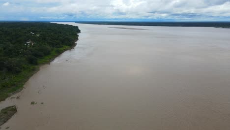 vista aérea que avanza, vista panorámica del agua marrón del río amazonas en colombia, cielo azul brillante en el fondo