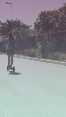 Spots-of-light-against-rear-view-of-african-american-woman-riding-electric-scooter-on-the-street