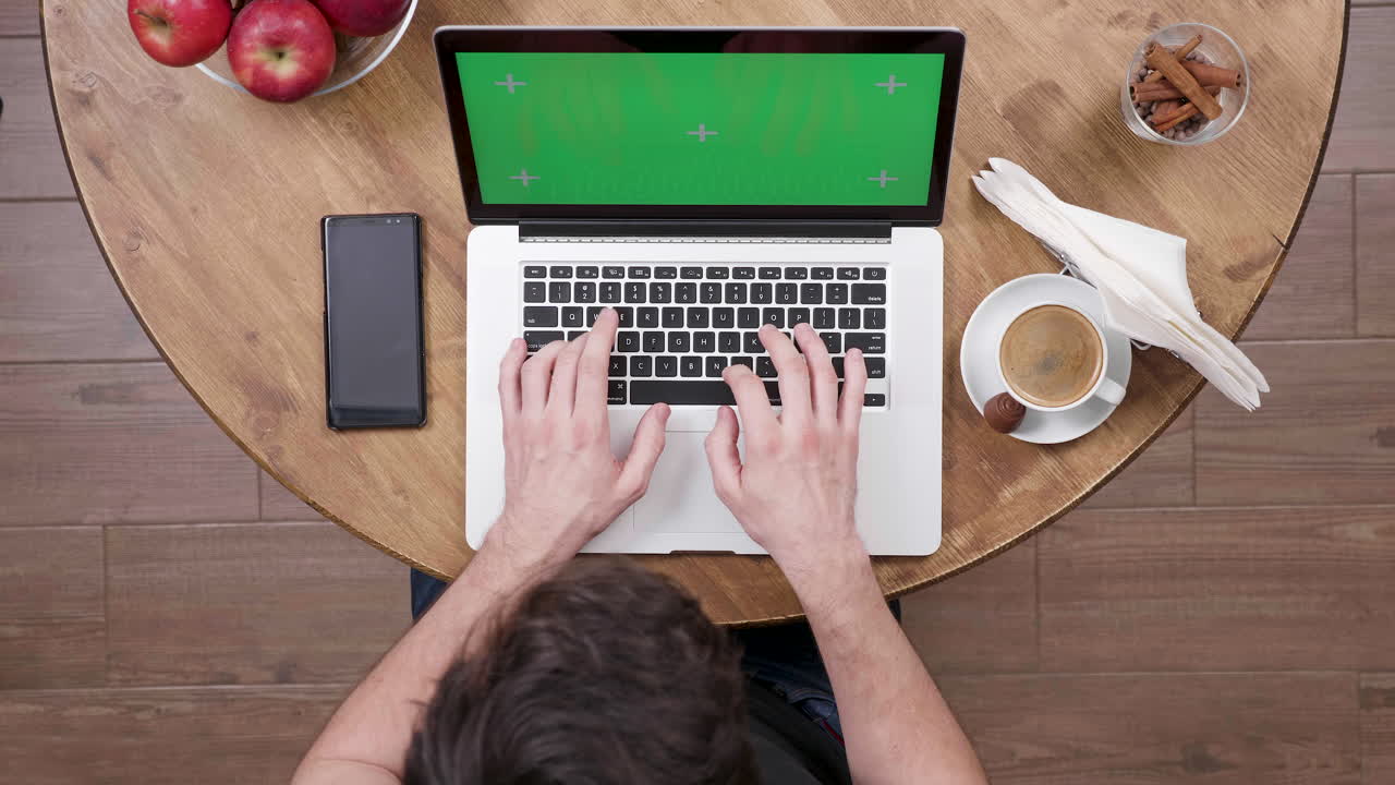 Person working on a laptop with coffee and apples on the table