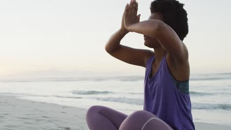 Mujer-Afroamericana-Practicando-Yoga-Y-Meditando-En-La-Playa-Soleada