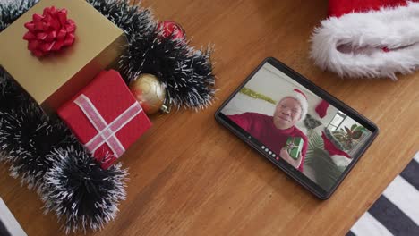 Smiling-albino-african-american-man-wearing-santa-hat-on-christmas-video-call-on-tablet
