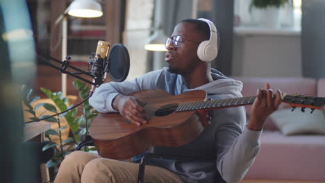 man in wheelchair singing and playing acoustic guitar in home studio